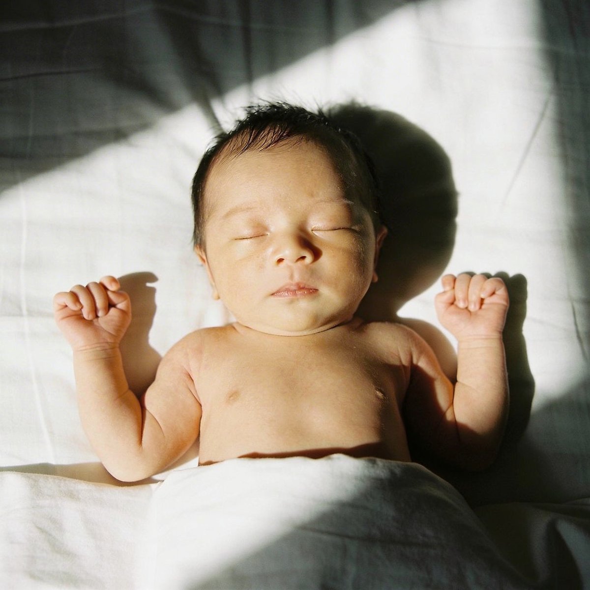 Newborn baby swaddled in cream fabric photographed in gentle window light in an Irish home studio