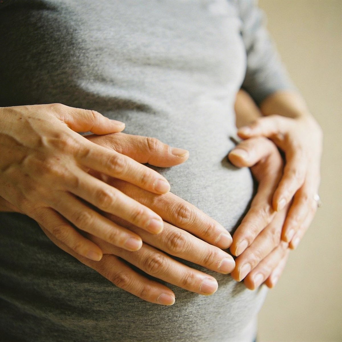 Hands forming a heart shape over a pregnant woman's bump, a tender moment during a maternity session in Ireland